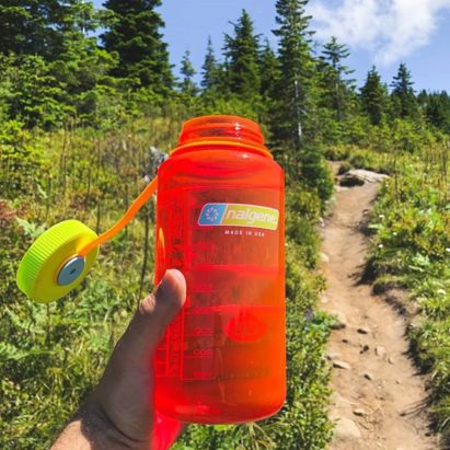 32oz Wide Mouth Sustain Pomegranate with single-track hiking trail in the background