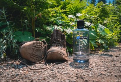 32 oz. Narrow Mouth bottle sitting on a dirt trail next to hiking boots