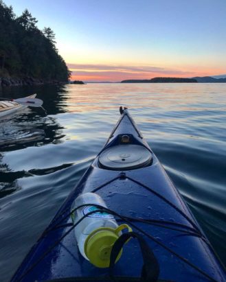 Kayaks on a glassy mountain lake at sunset