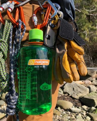 32oz Narrow Mouth Sustain Melon Ball attached to a clip on a hiker's backpack