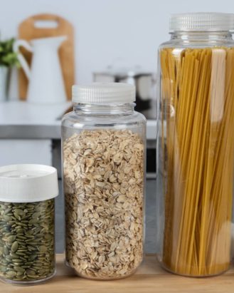Three different sized storage bottles filled with dry foods sitting on top of a kitchen counter