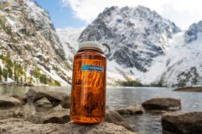 32 oz Wide Mouth Bottle Sitting on a rock in front of a mountain lake