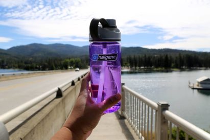 Focus on 20 oz. Screw Top - Purple with arm extended over a bridge walkway
