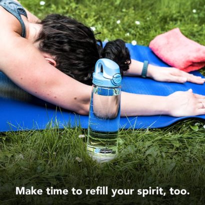 Woman doing yoga on a grassy surface with 24 oz. OTF bottle - clear with seaport cap