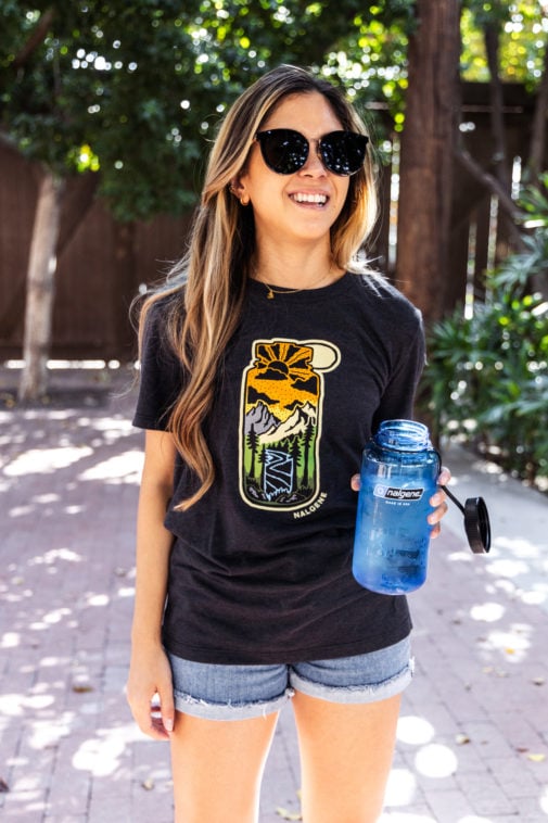 Lifestyle image of female in Atomic Child and Nalgene shirt collaboration with Water Bottle