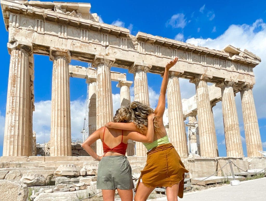 Two girls standing in front of the ruins of the Parthenon in Athens, Greece