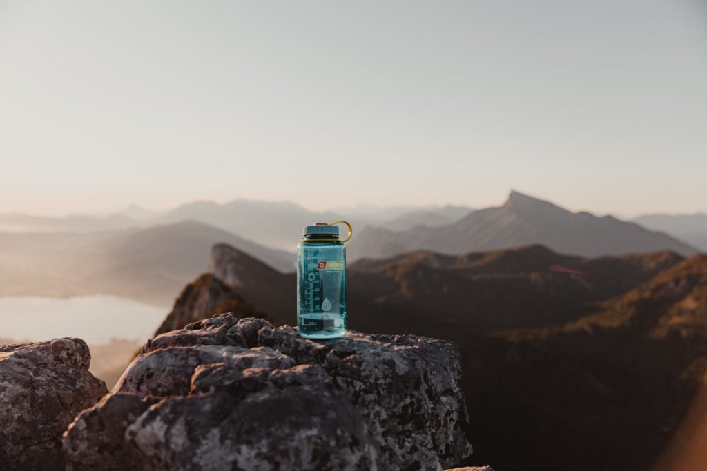 Cerulean 32oz Wide Mouth Nalgene bottle sitting on a roack overlooking a mountain range