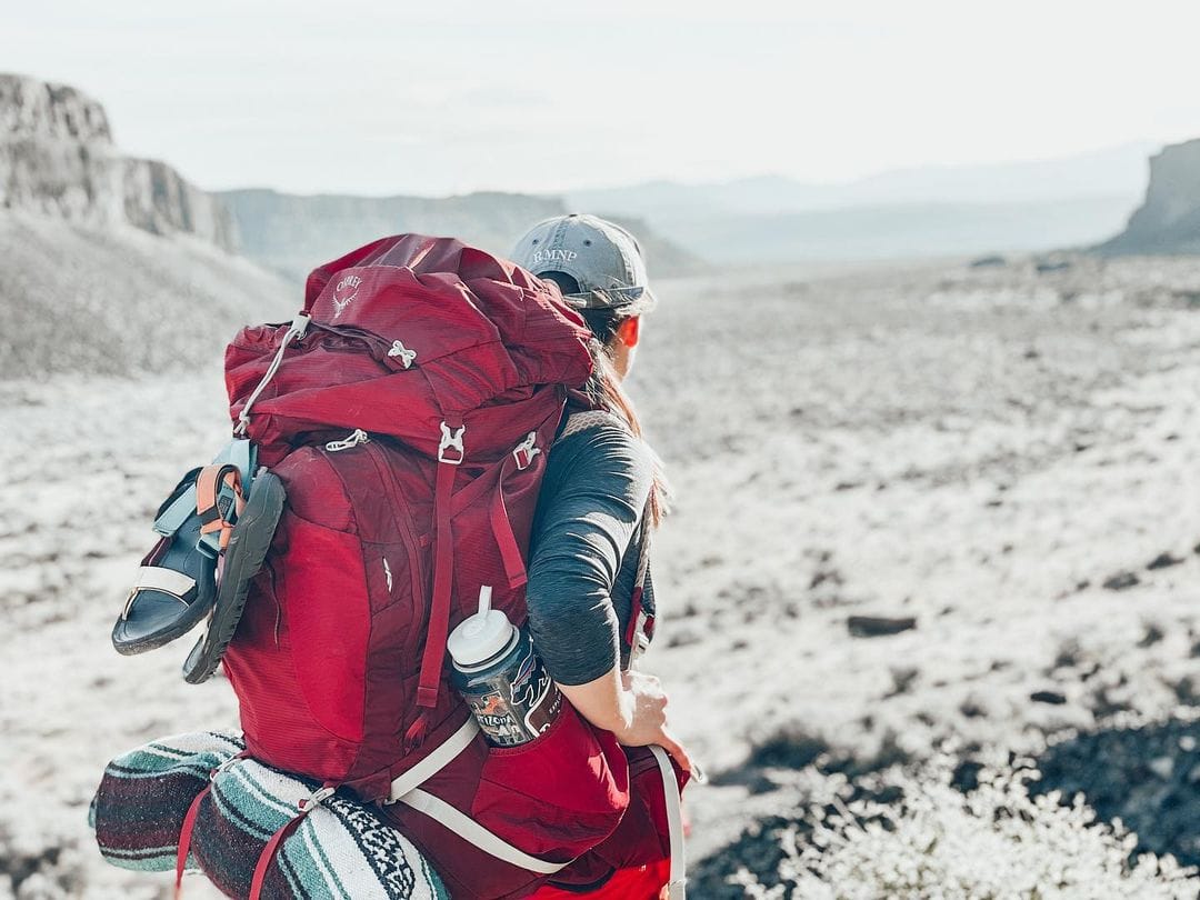 Person wearing a red backpacking pack with a 32 oz wide mouth Nalgene in the side pouch